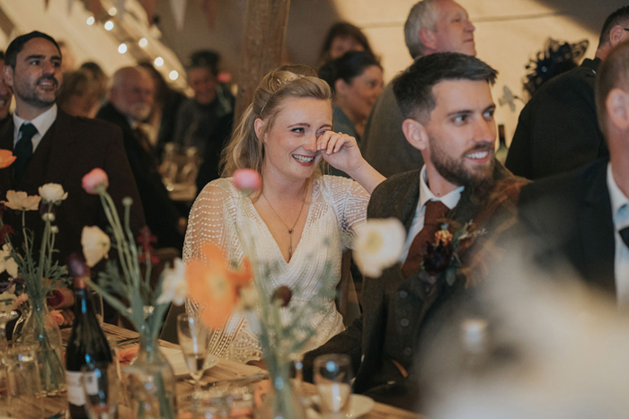 Bride wipes tears while listening to wedding speeches