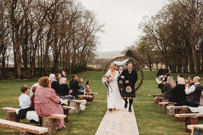 Bride and groom walk aisle during outdoor ceremony