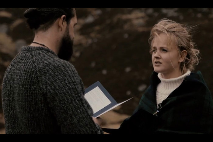 still from film of couple reading wedding vows to each other