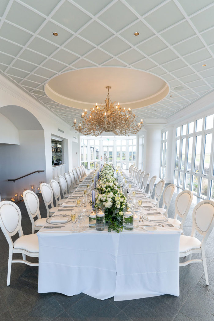 an elegant light filled room with ornate chandelier hanging over a long table set for a wedding at Old Course Hotel