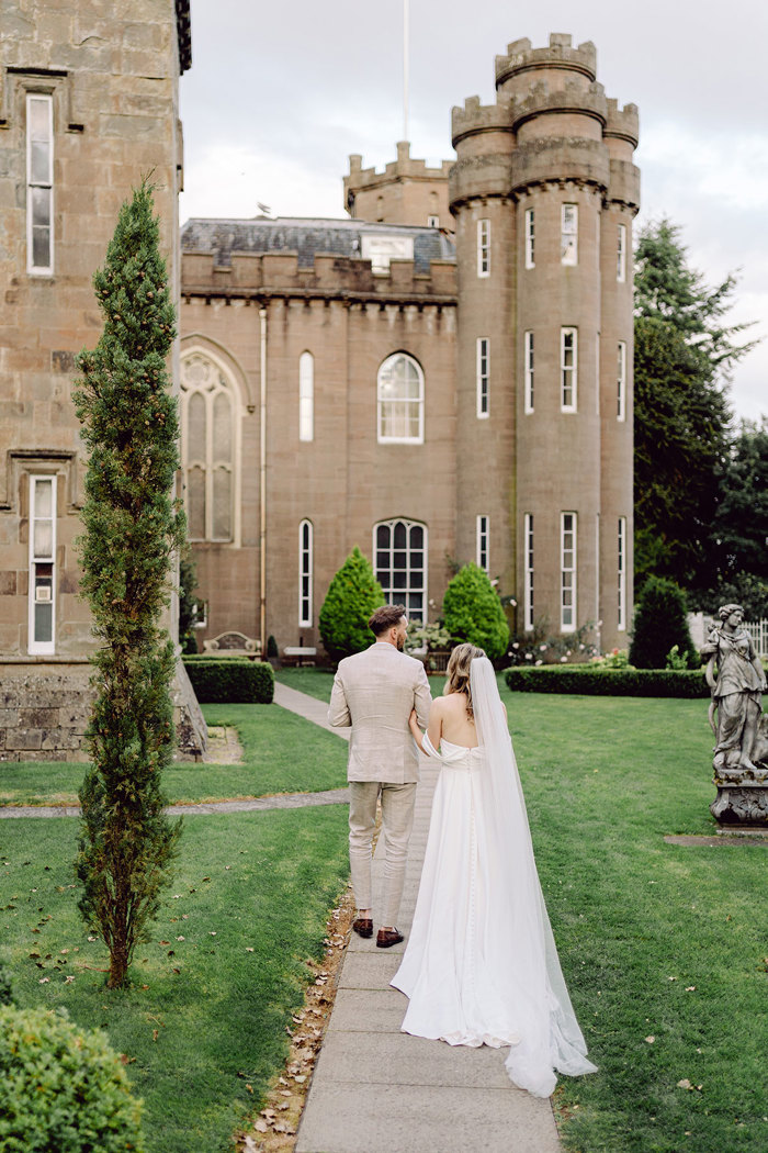 bride and groom walk towards drumtochty castle