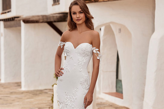 woman wearing a sweetheart neckline wedding dress including 3D floral detailing and decorative shoulder trailing straps