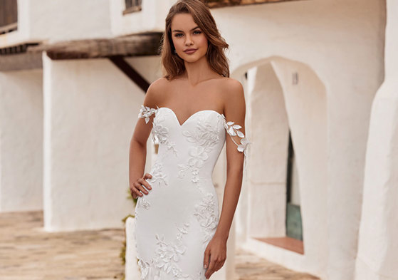 woman wearing a sweetheart neckline wedding dress including 3D floral detailing and decorative shoulder trailing straps