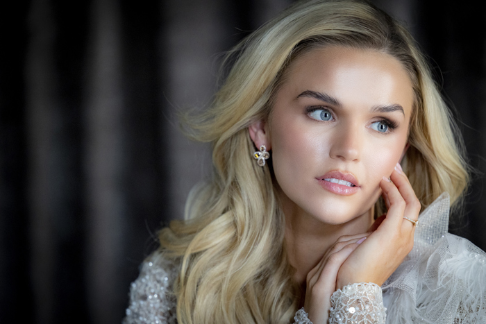 A close up of a blonde woman with her hand against her cheek looking off to the side