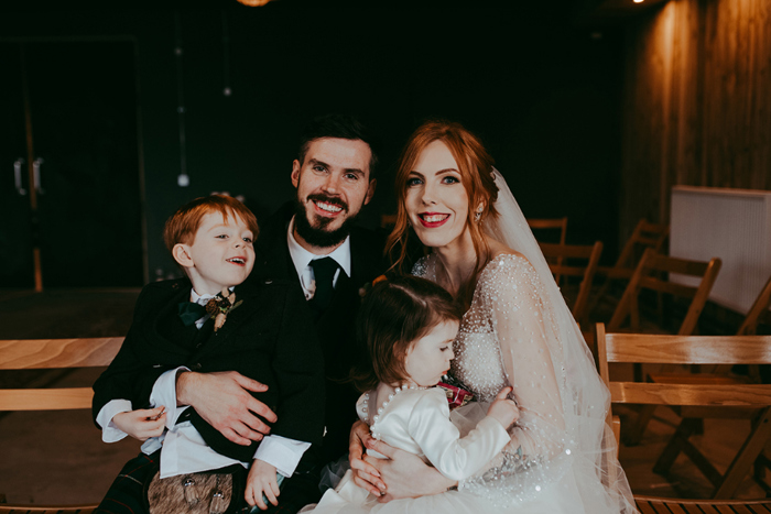 Newlywed couple and their children smile for family portrait