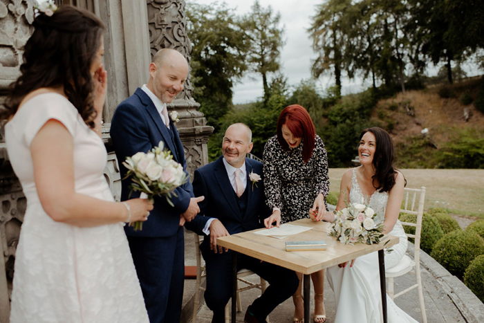 Bride and groom sign register outside at The Orangery 