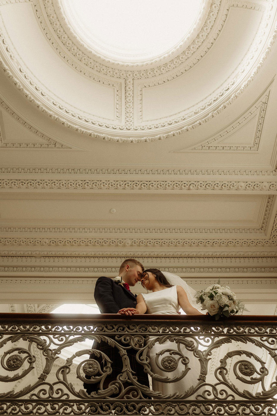 bride and groom pose against backdrop of ceiling at kilmardinny house in bearsden