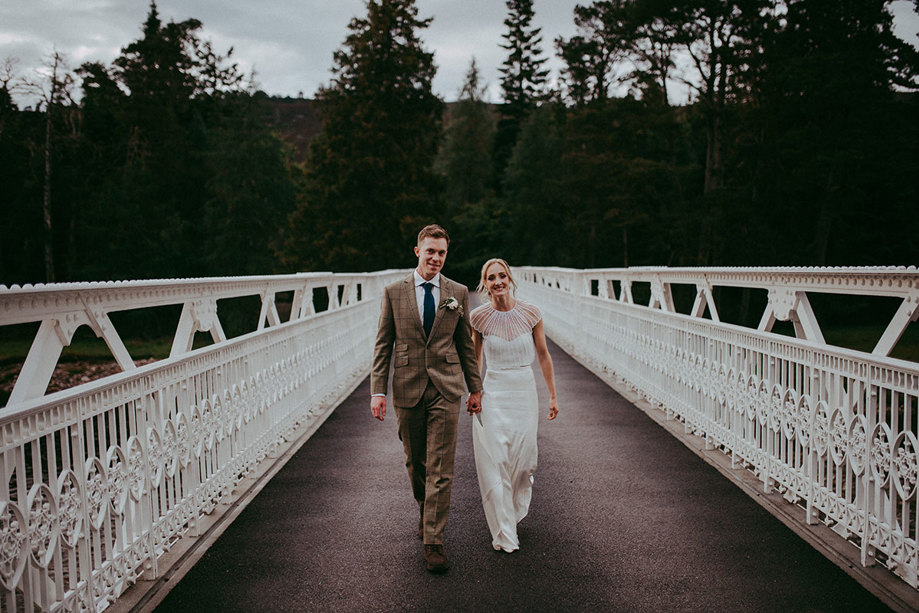 bride and groom walking across white bridge at mar lodge