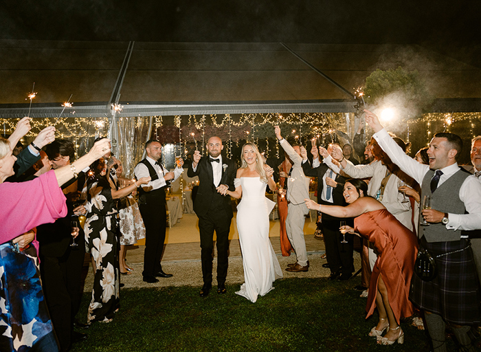 a bride and groom sparkler procession outside a fairy light filled marquee at night