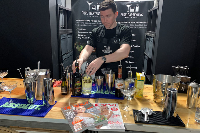 Man behind cocktail bar surrounded by drinks and cocktail shakers