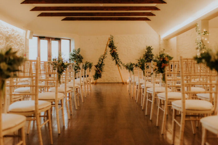 looking down an aisle with a wooden arch at the top and seats on either side