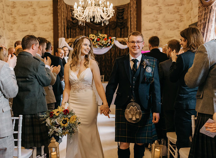 A bride and groom holding hands as they walk down the aisle together