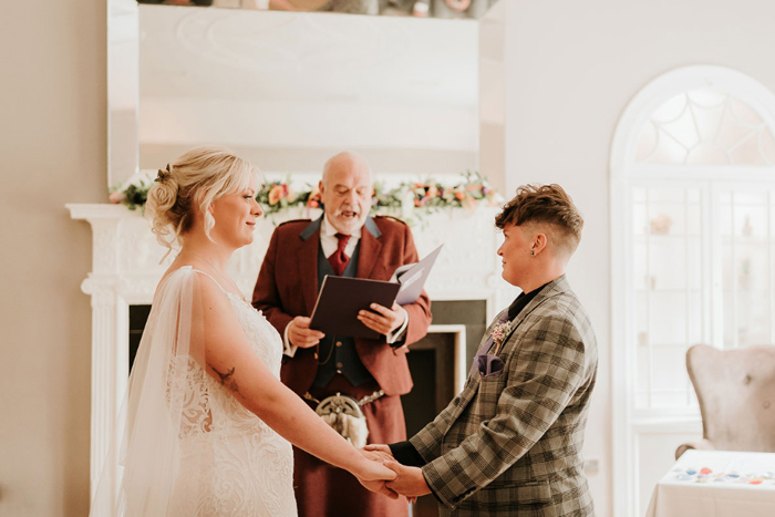 Brides hold hand during the ceremony