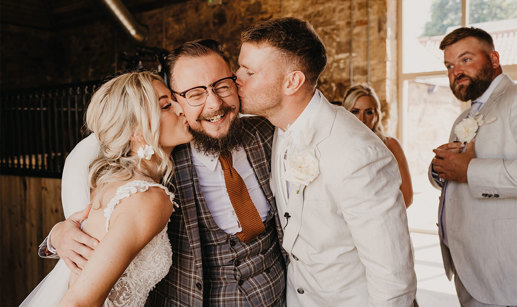 Bride and groom kissing man on cheek