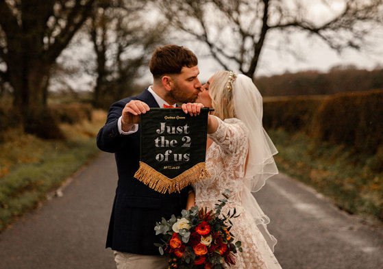 Couple elope to Gretna Green in Dumfriesshire holding up sign and kissing