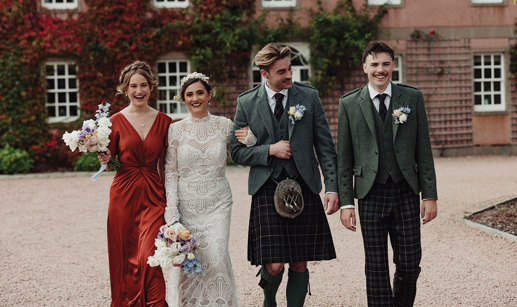 Groom and usher wearing outfits from McCalls walking beside bride and bridesmaid