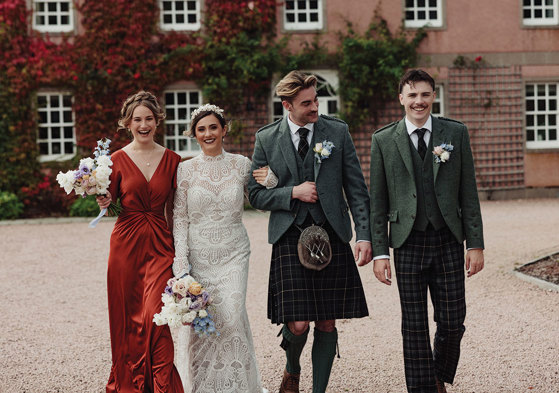 Groom and usher wearing outfits from McCalls walking beside bride and bridesmaid