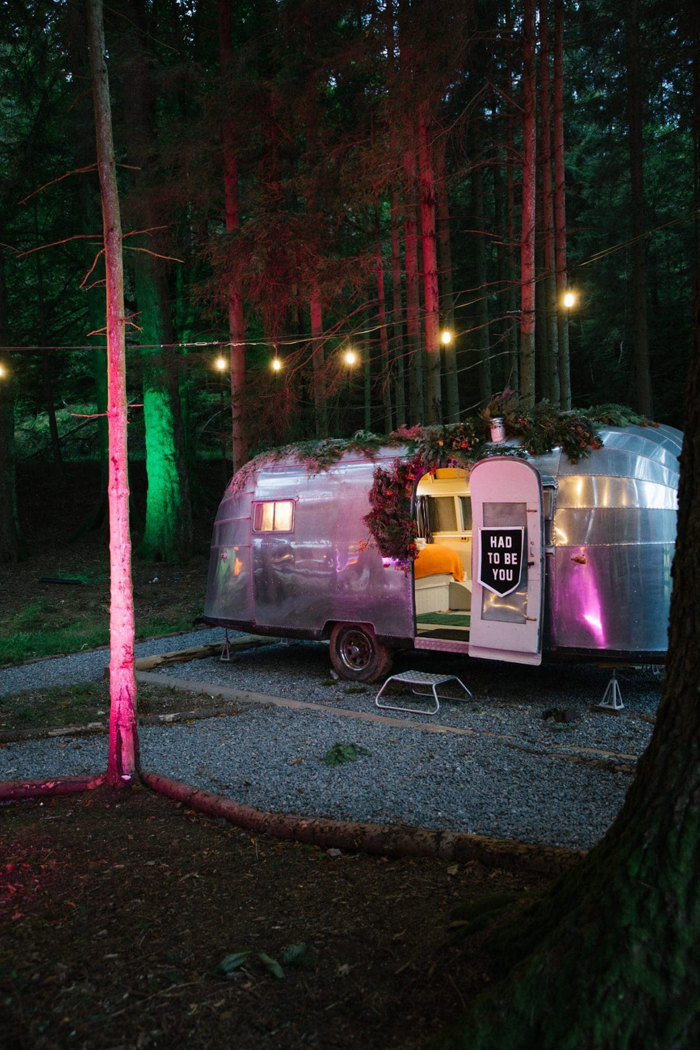 A silver trailer with a door open in the middle of trees at Glen Dye Cabins and Cottages.