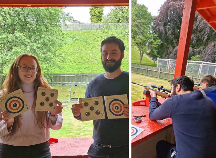 On the left a man and a woman stand next to each other holding up two paper targets each with holes in them, on the left a man uses and air rifle gun