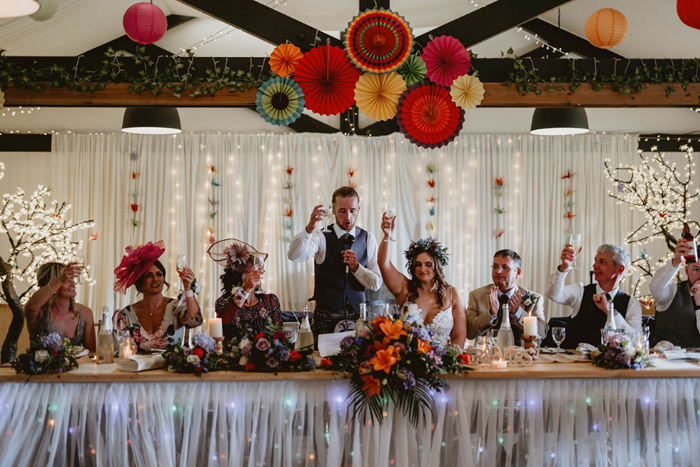 Top table raise their glasses in a toast during groom's speech