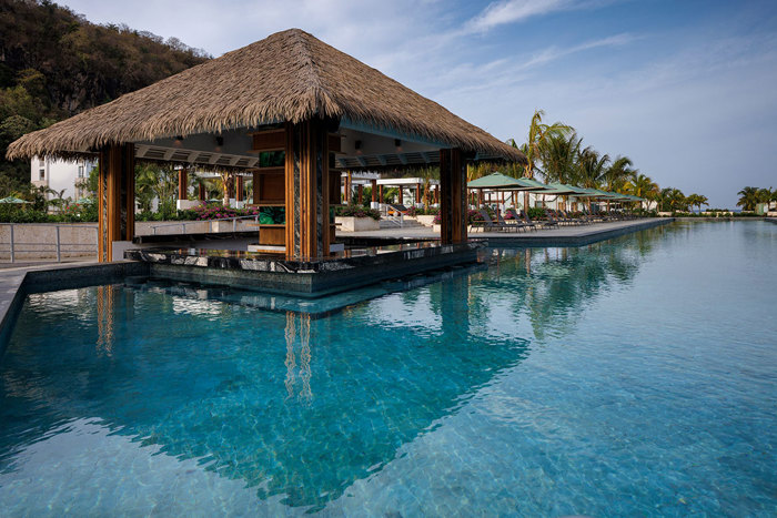 A pool with a hut and umbrellas