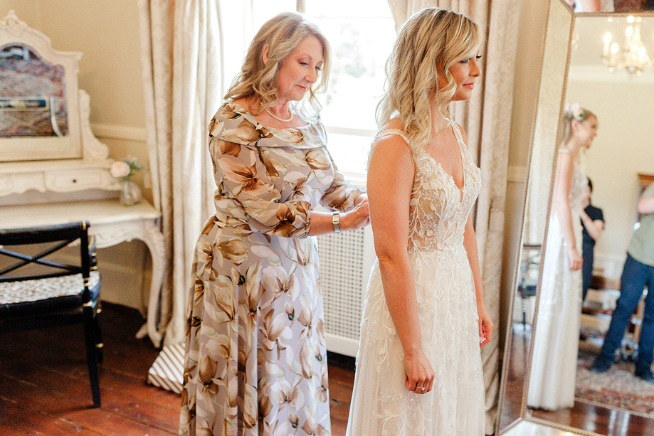 Bride being helped with wedding dress on wedding morning