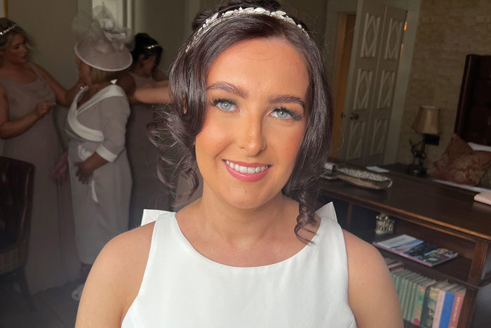 blue-eyed brunette bride smiles to camera showing off her makeup and the front of her dress