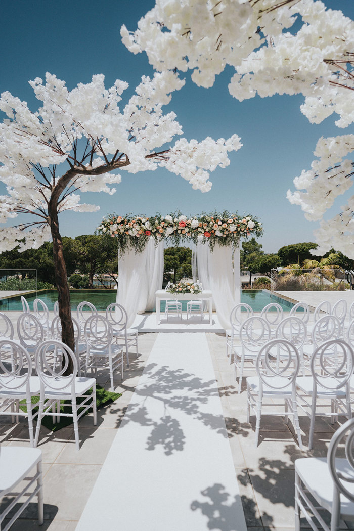 a white wedding ceremony set up outside with blossom trees at Quinta do Lago Portugal