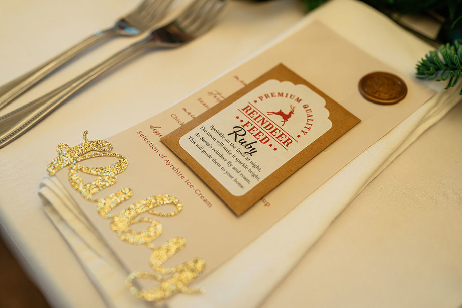 a table setting for 'Ruby' includes sparkly gold letters spelling her name, a personalised menu and a sachet of 'reindeer feed'