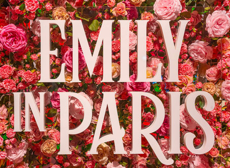 'Emily in Paris' signage in front of a wall of pink and red flowers