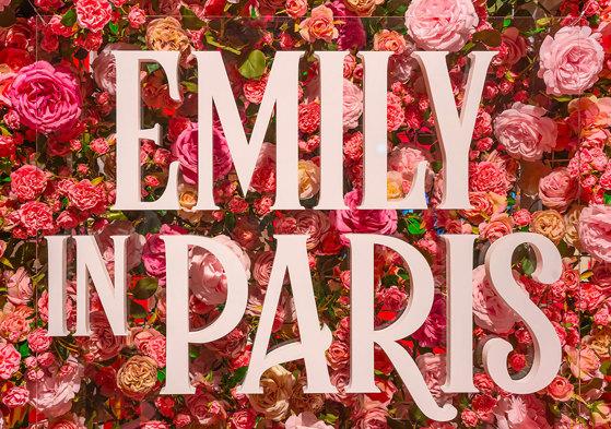 'Emily in Paris' signage in front of a wall of pink and red flowers