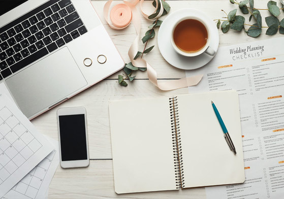 books phone and notepad strewn across desk with laptop