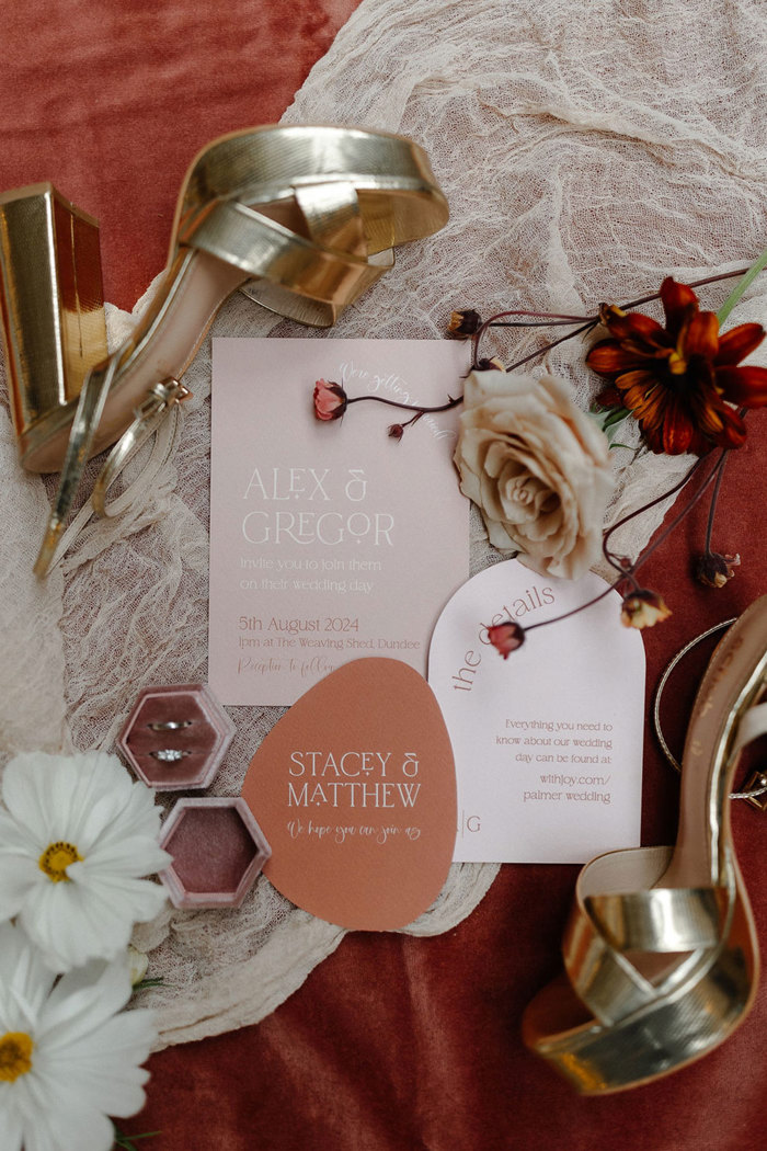 flatlay detail shot of red, pink, white and gold heels, flowers, stationary and rings for a wedding day