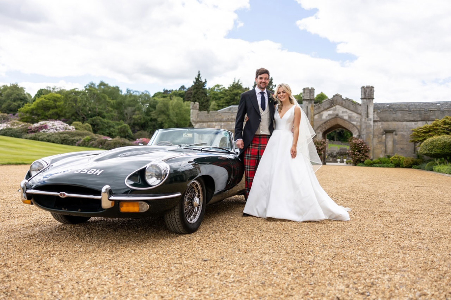 Couple stand beside vintage Jaguar car