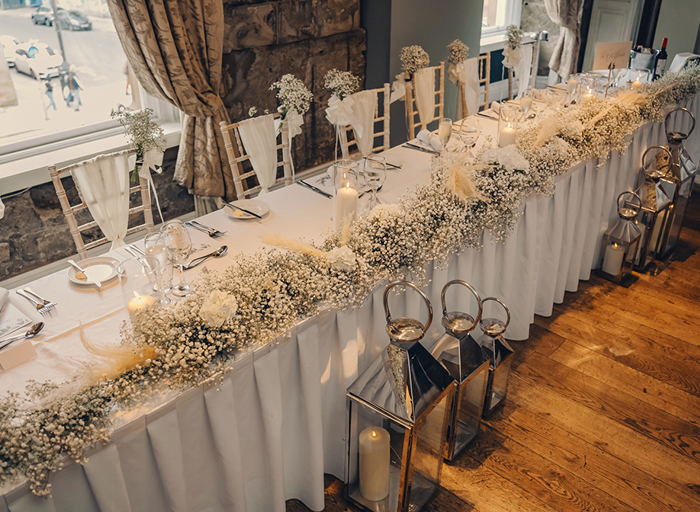 white top table with flowers and white chairs