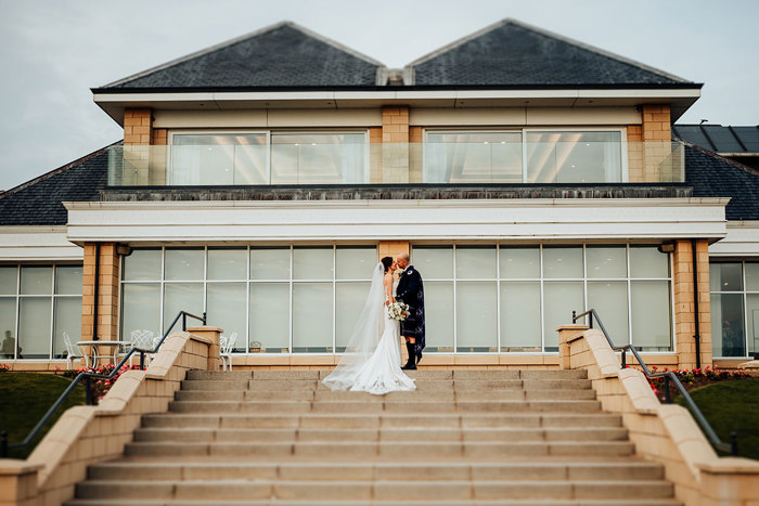 a bride and groom kiss on a staircase outside Seamill Hydro