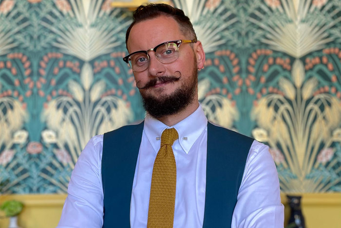 Man with mustache and glasses wearing shirt and tie