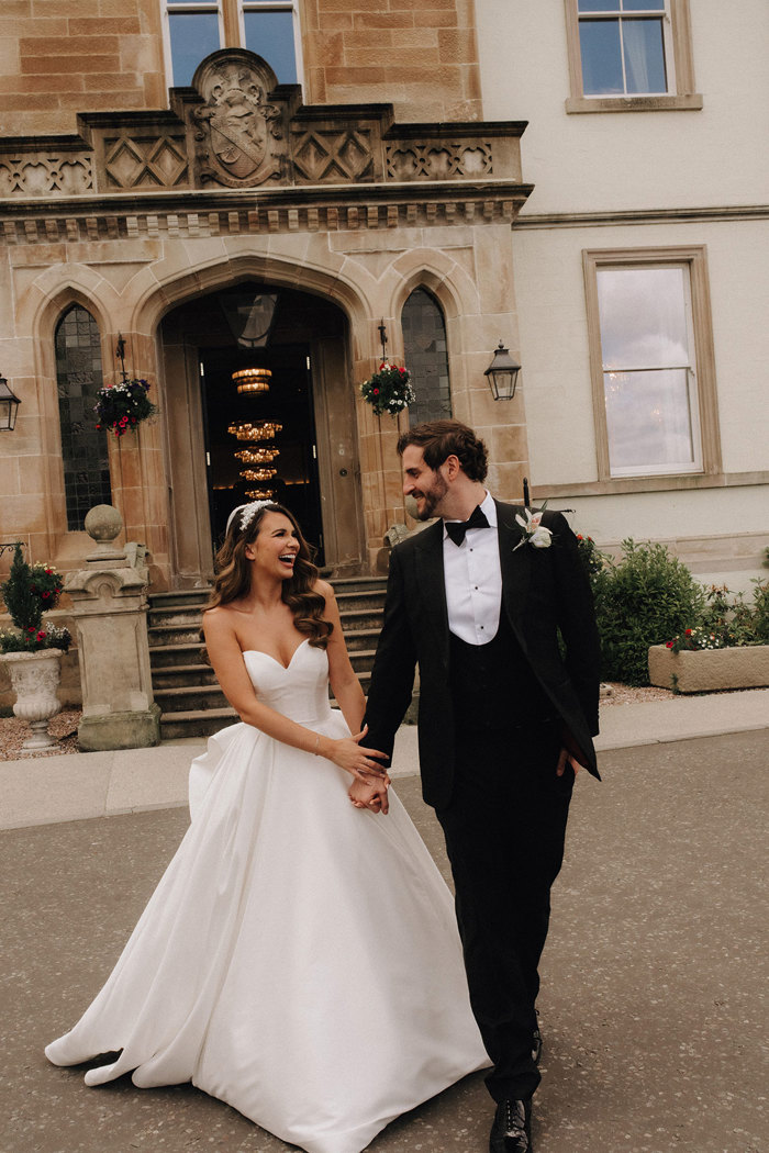 a bride and groom walking hand in hand outside Cameron House.