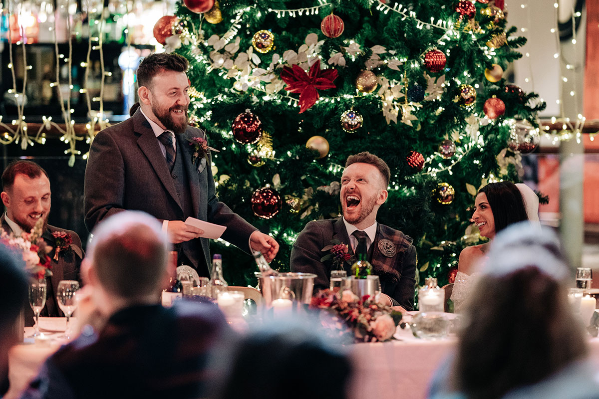 groom laughs as best man gives wedding speech during dinner at oran mor
