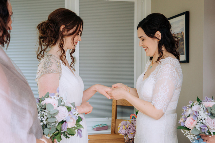 Two brides exchanging rings during ceremony