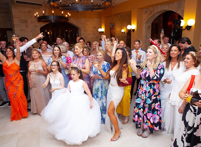 a group of happy and cheering wedding guests on a dance floor