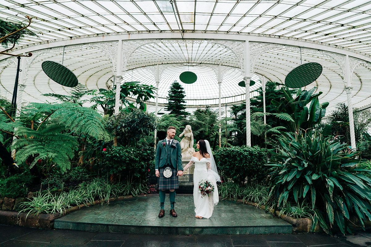 bride and groom hold hands in glasgow botanic gardens