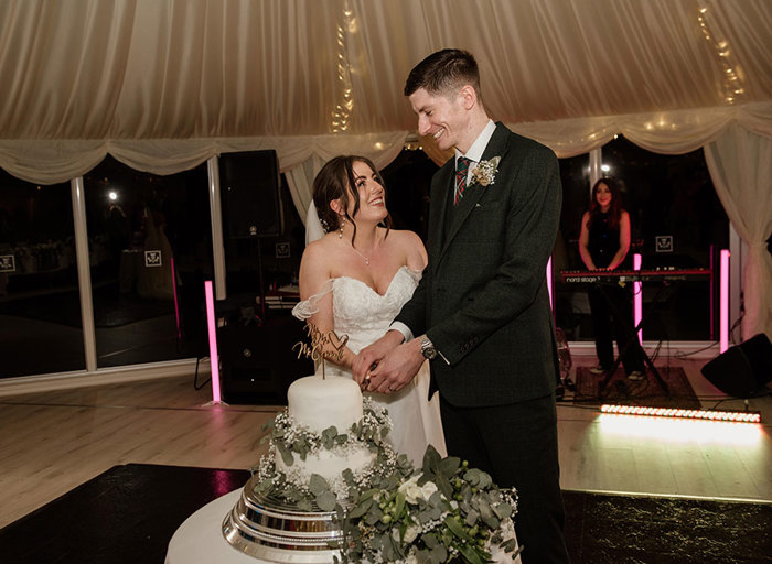 A bride and groom cutting their two-tier wedding cake 