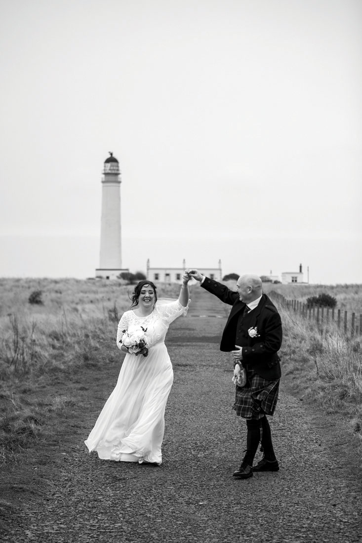 Black and white picture of bride and groom dancing outdoors at wedding