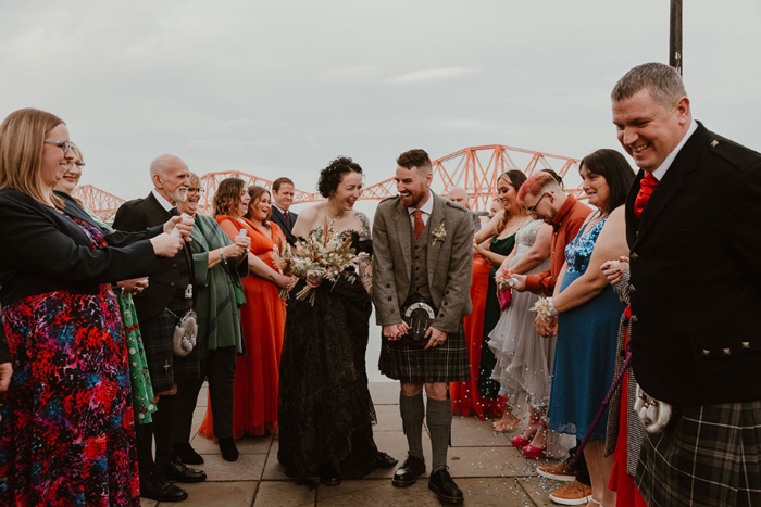 Bride and bridesmaid walk through guests after confetti shower