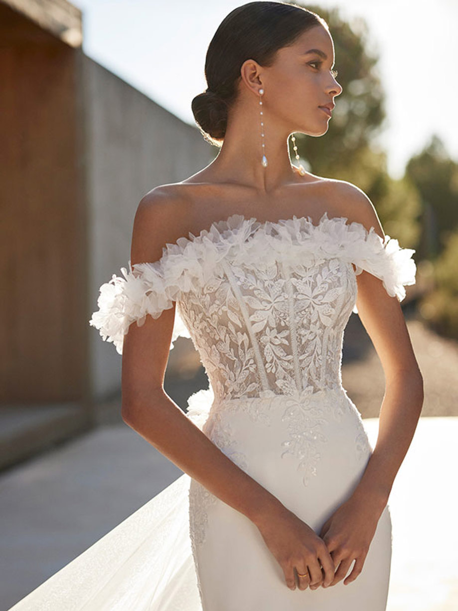 close up front facing model wearing shimmery off the shoulder wedding dress