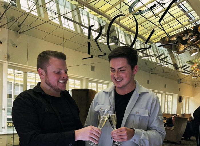 two men clinking champagne flutes in front of a mirror at ROX in Glasgow