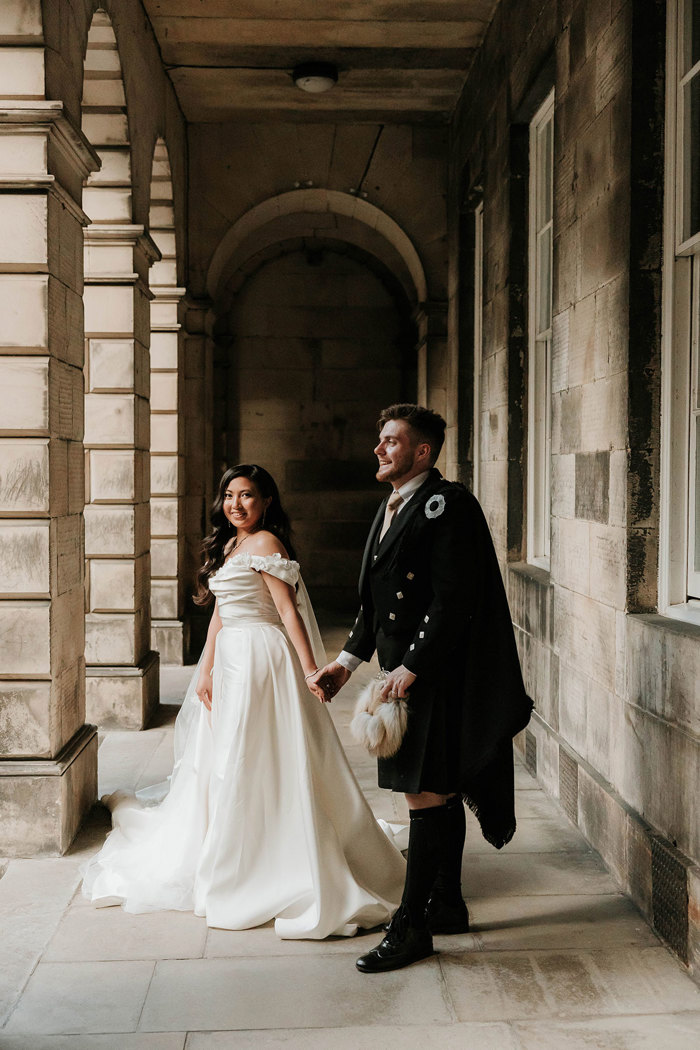 bride looking towards camera and holding grooms hand signet library