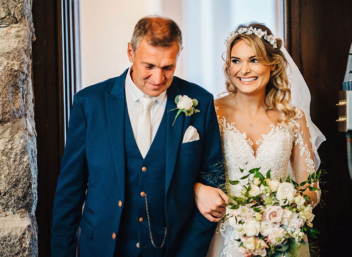 Father walks with his daughter, the bride, arm in arm