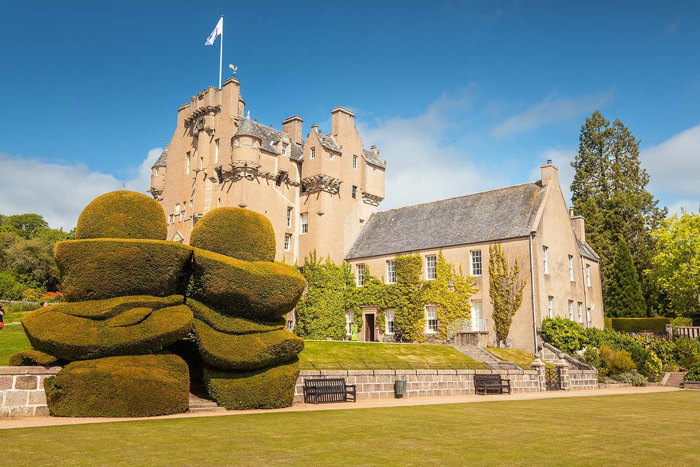 exterior of crathes castle with green lawn and trees